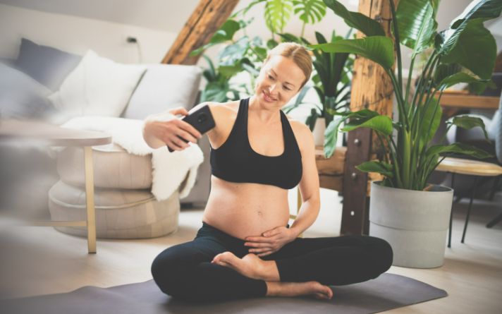 woman taking a photo of herself while working out after pregnancy.